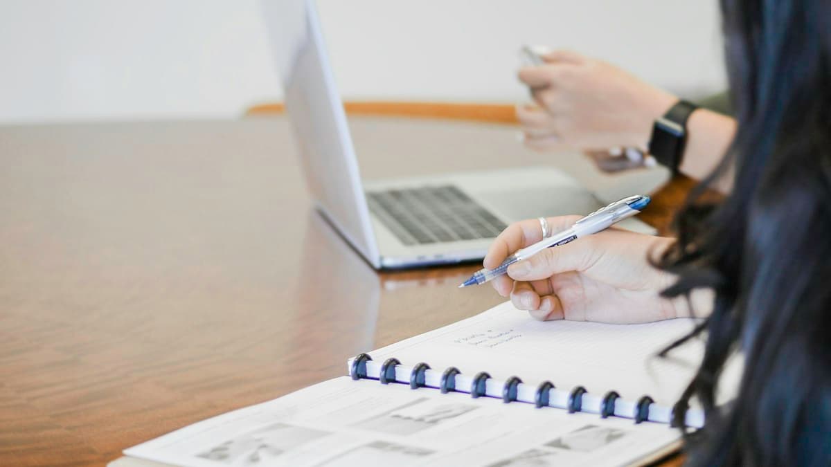 A hand filling in a form with a pen